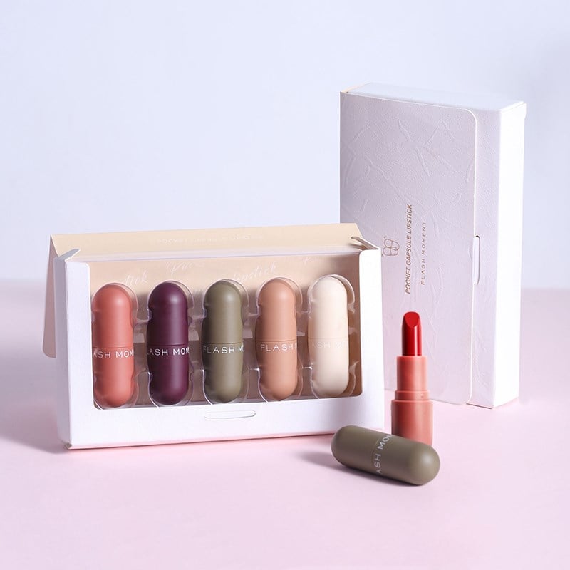 Set of five compact capsule-style velvet lipsticks in various earth tones and berry shades, with a bright red open tube.