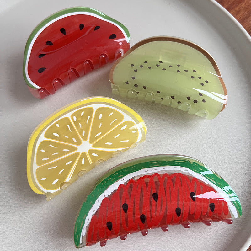 Four semi-circular fruit-themed acrylic hair claws featuring watermelon, kiwi, and lemon slice designs on a white plate.