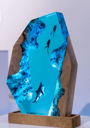 Illuminated resin and wood night light featuring blue water, rocky sides, two scuba divers, and a shark.