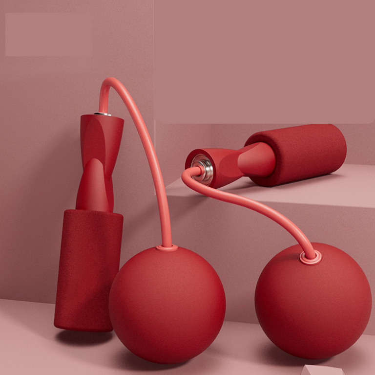 Red cordless jump rope set with foam-covered handles and weighted ball attachments on a matching monochromatic background.