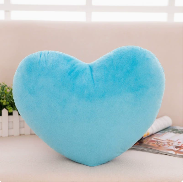 A plush, bright blue heart-shaped pillow resting on a light-colored sofa.
