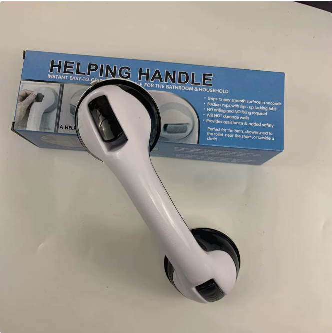 White and black suction-mount safety grip bar with locking tabs, positioned in front of its blue product packaging.
