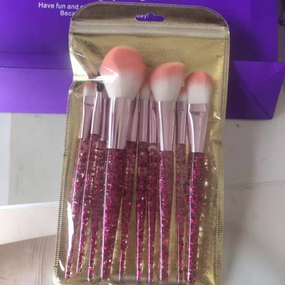 10-piece makeup brush set in a gold pouch, featuring pink glitter handles, rose gold ferrules, and soft ombré bristles.