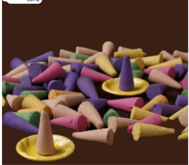 A collection of colorful incense cones in purple, pink, yellow, and beige, with two cones resting on small yellow plates.