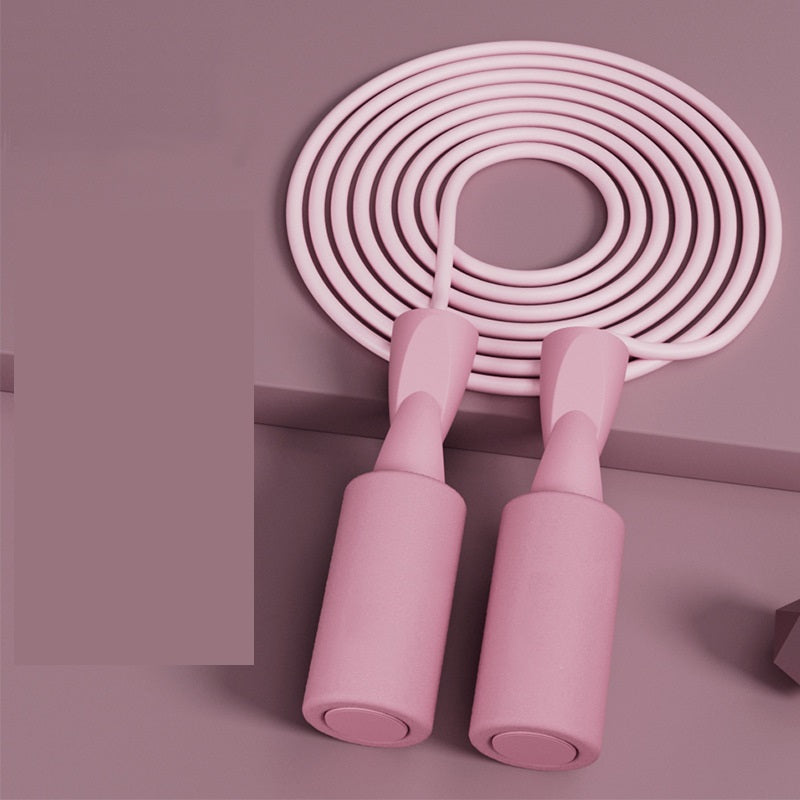 Minimalist blush pink jump rope with smooth, matte-finish handles, neatly coiled against a matching monochrome background.