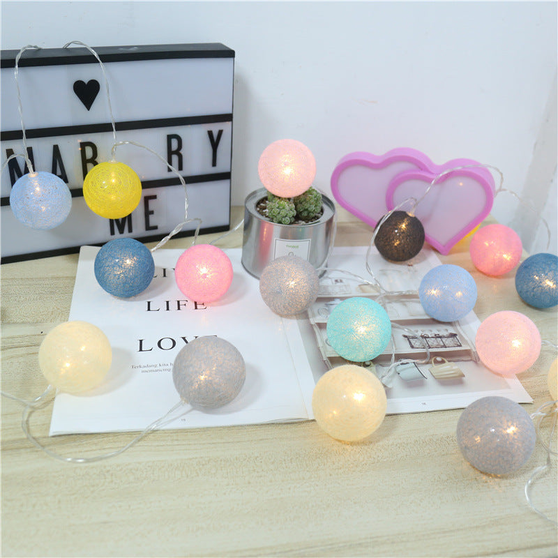 Multicolor LED string lights with textured, spherical cotton shades in pastel pink, blue, yellow, and grey.