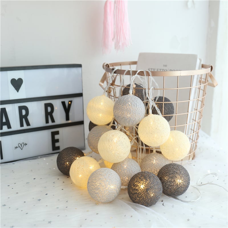 String of LED cotton globe lights in white, cream, and gray, styled with a wire basket and decor on a starry cloth.