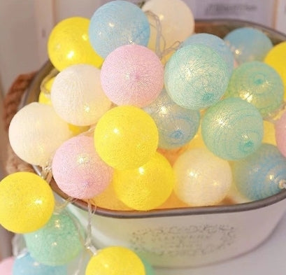 Pastel cotton LED lantern string lights in yellow, pink, blue, and white, piled in a decorative metal bucket.