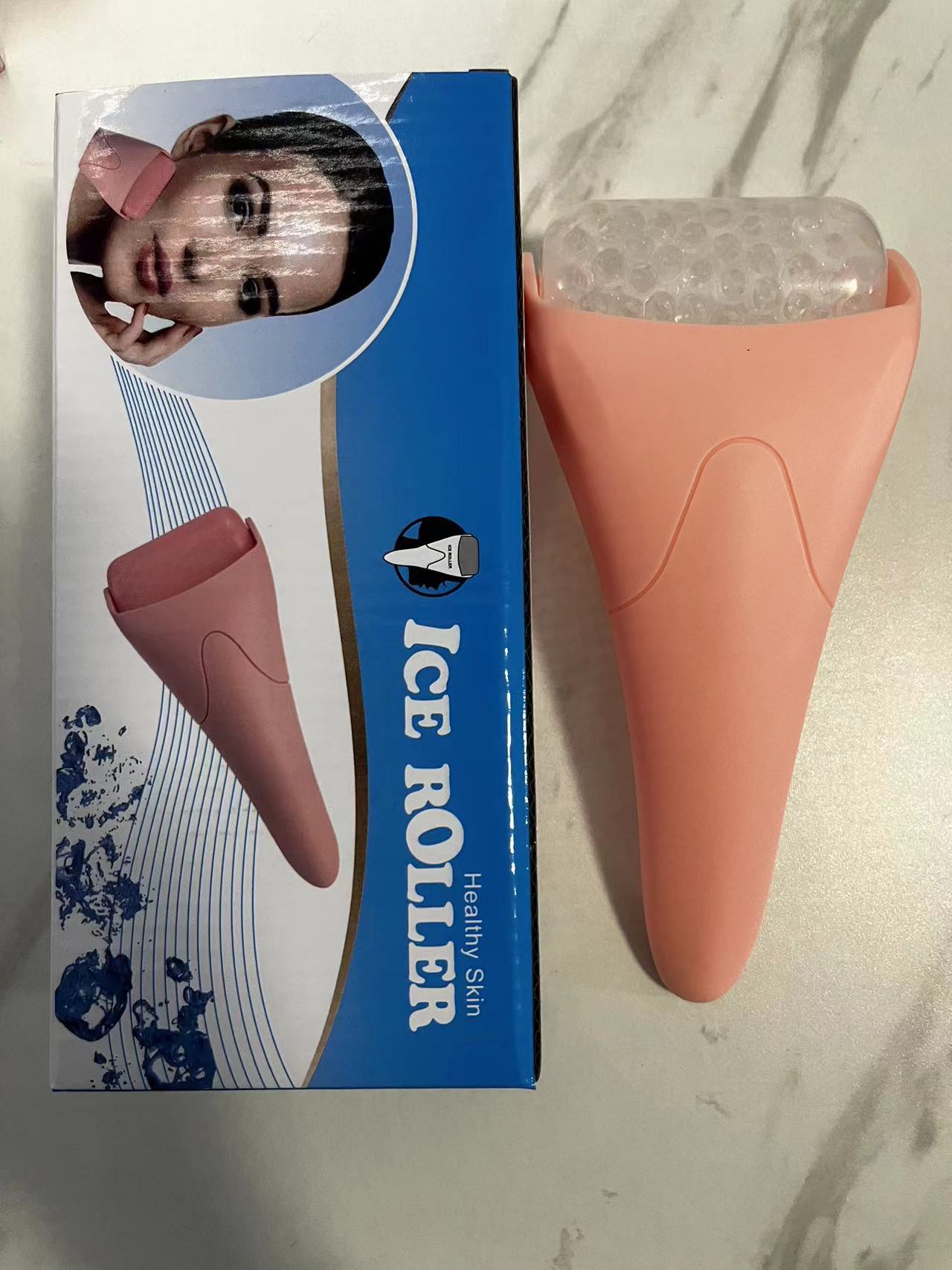 Chill Glide facial ice roller with a peach-pink handle and a textured, clear cooling roller head, next to its box.