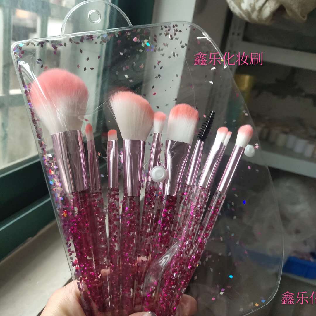 10-piece makeup brush set with pink glitter handles, metallic pink ferrules, and soft white-and-pink tipped bristles.