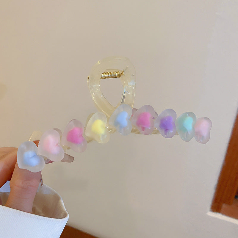 Clear hair claw clip adorned with translucent, pastel-colored hearts in blue, pink, yellow, and purple.