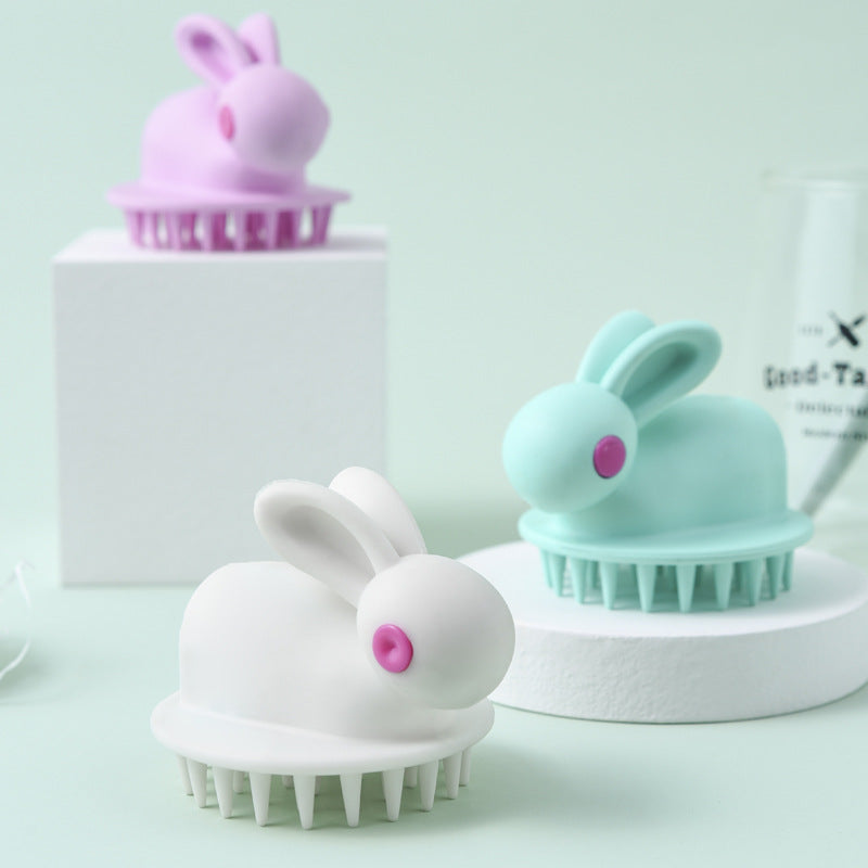 Three rabbit-shaped kids' scalp brushes in white, pastel blue, and lavender, each featuring pink button-style eyes.
