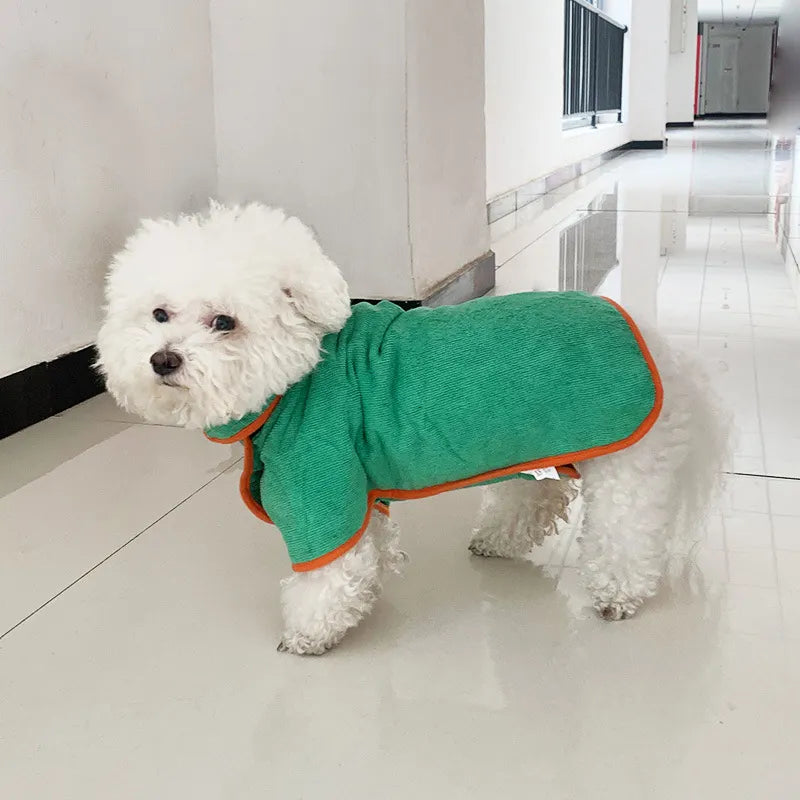 Small white curly-haired dog wearing a textured green quick-dry pet bathrobe with vibrant orange trim.