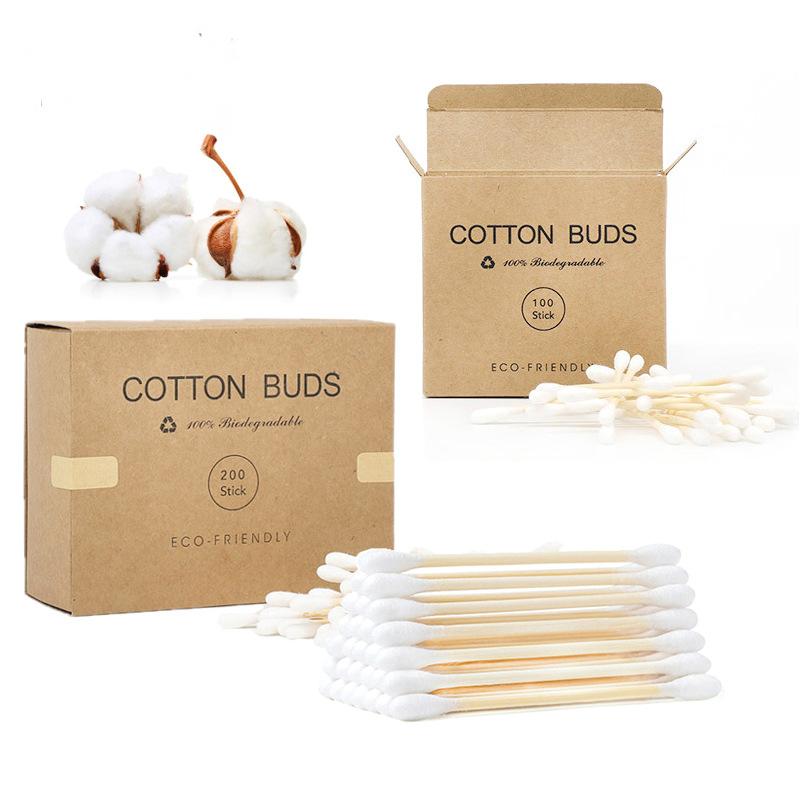Eco-friendly bamboo cotton swabs in brown cardboard boxes, accompanied by white cotton bolls on a white background.