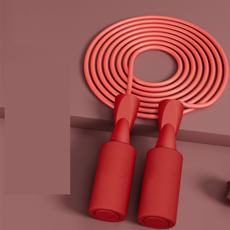Coral pink VersaRope jump rope with minimalist matte red handles coiled on a matching dark pink background.