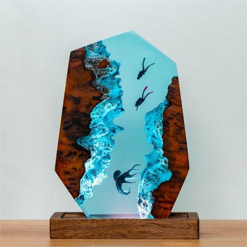 Octopus and two scuba divers suspended in blue epoxy resin between jagged wood canyon walls on a wooden base.