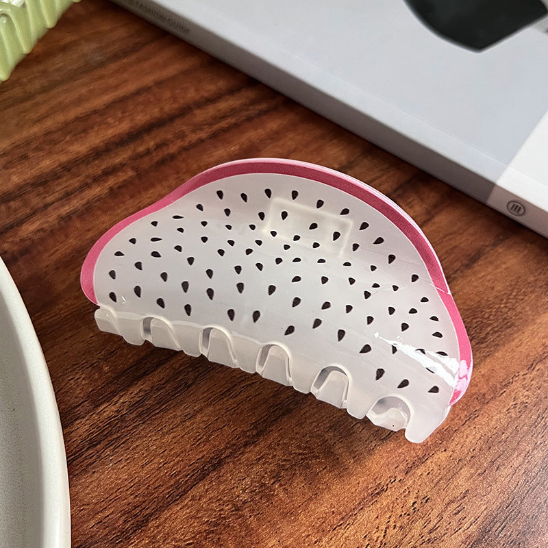 Dragon fruit-inspired acrylic hair claw in translucent white with black seeds and a bright pink rim.