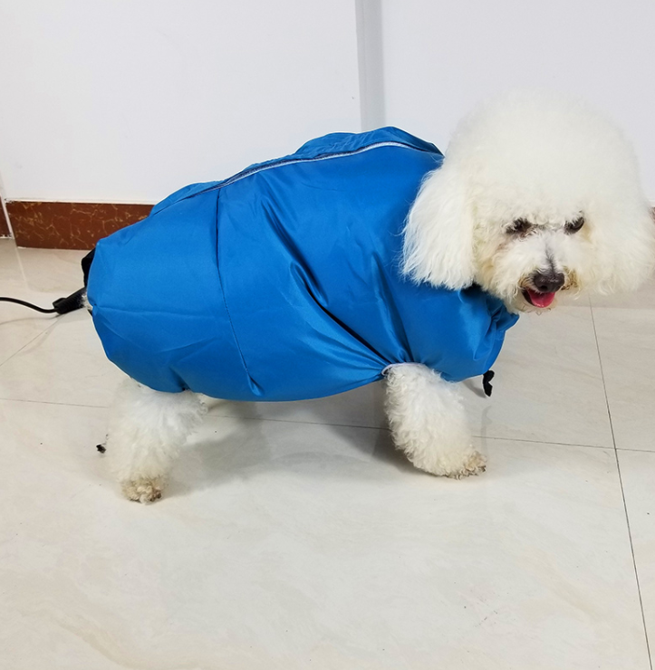 A fluffy white dog wearing a bright blue, zip-up pet grooming dryer bag on a tiled floor.
