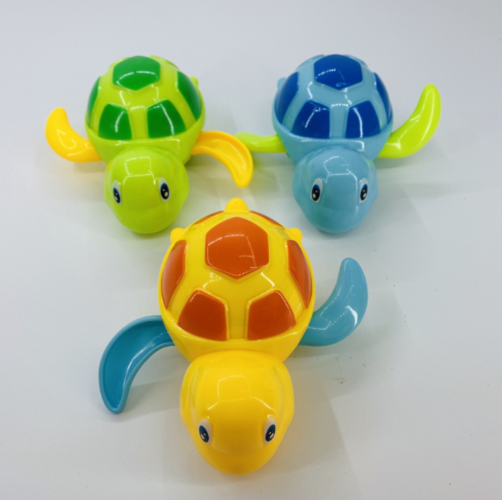 Three colorful plastic turtle wind-up bath toys in green, blue, and yellow on a white surface.
