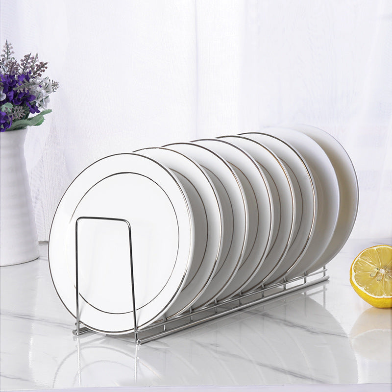 Minimalist stainless steel dish rack holding a row of white plates with thin silver rims on a white marble surface.