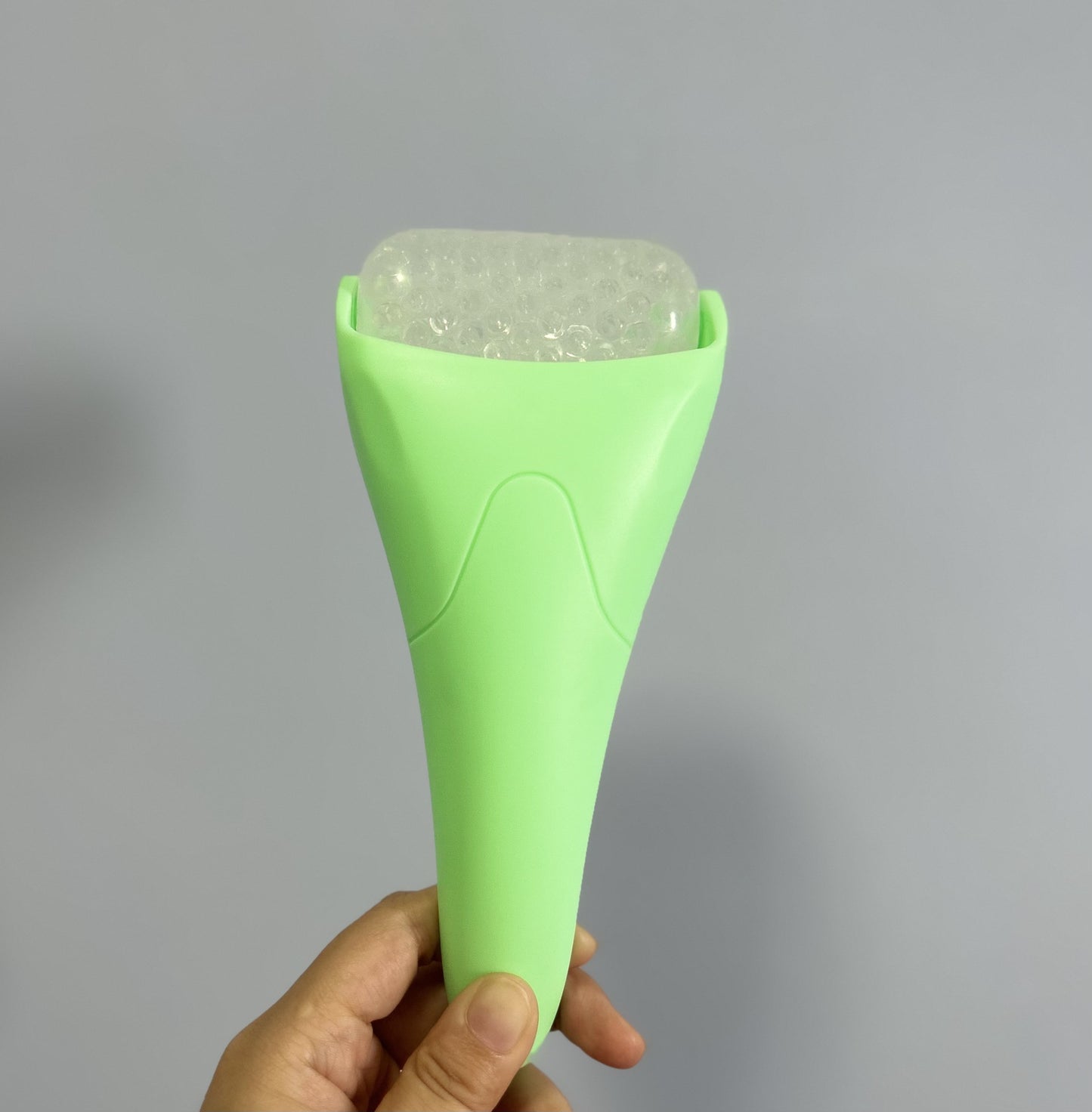 Light green Chill Glide facial ice roller with a textured gel bead barrel, held against a neutral gray background.