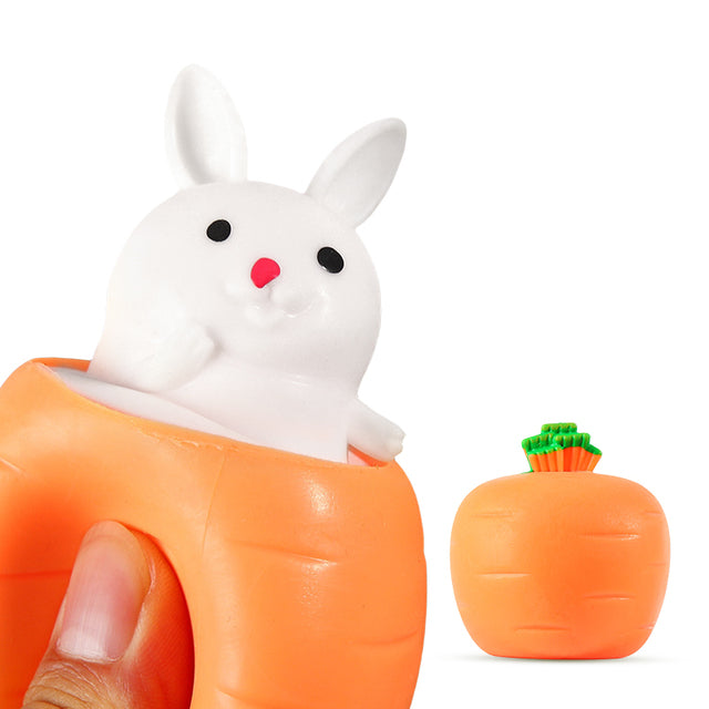 White toy bunny pops out of an orange carrot squeeze stress reliever toy against a white background.