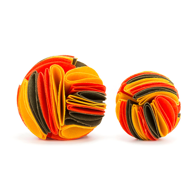 Two interactive felt dog snuffle balls in orange, yellow, and olive green fabric strips, isolated on white.