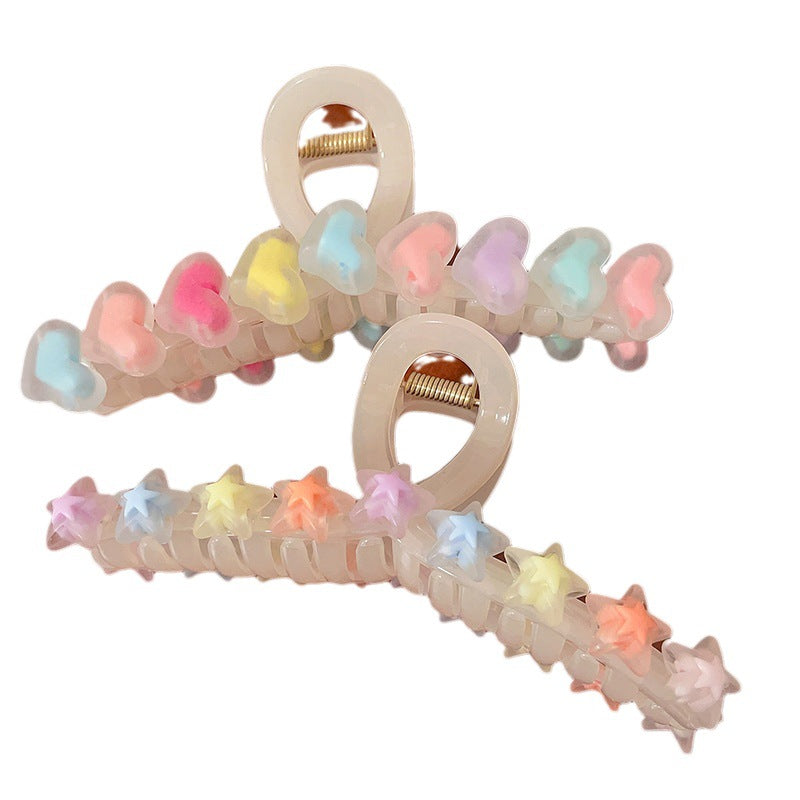 Two translucent beige hair claw clips decorated with colorful pastel heart and star charms.