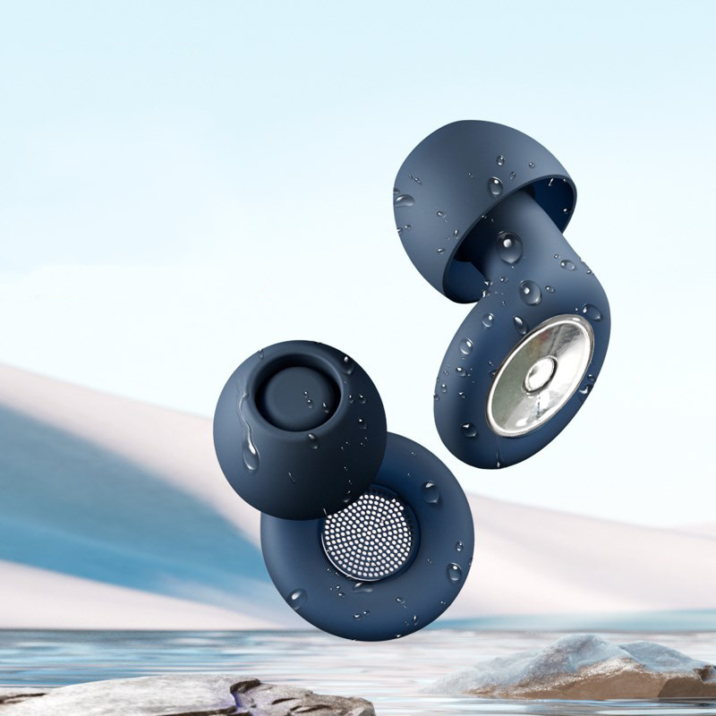 Dark blue, moisture-covered Silent Night earplugs with a metallic speaker mesh, floating against a calm beach backdrop.