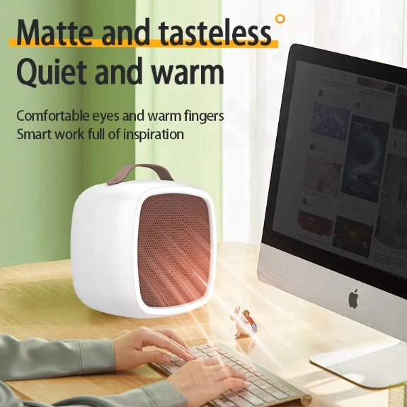 Compact white 500W desktop heater with brown leather handle and glowing orange mesh front on a wooden desk.