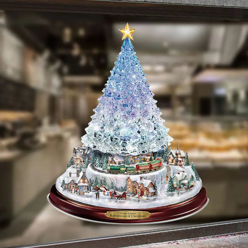 Christmas window decal featuring a crystalline, glowing blue tree atop a miniature snowy village with a moving train.