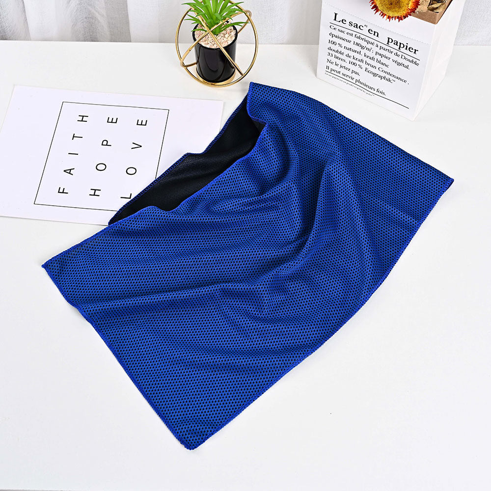 SwiftCool blue mesh outdoor cooling towel with a black interior, displayed on a desk next to decor.