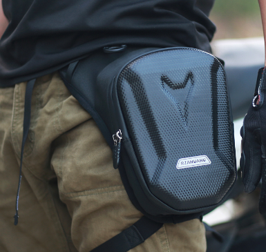 Black waterproof leg messenger bag with a carbon fiber texture, molded hard-shell design, and a zip closure.