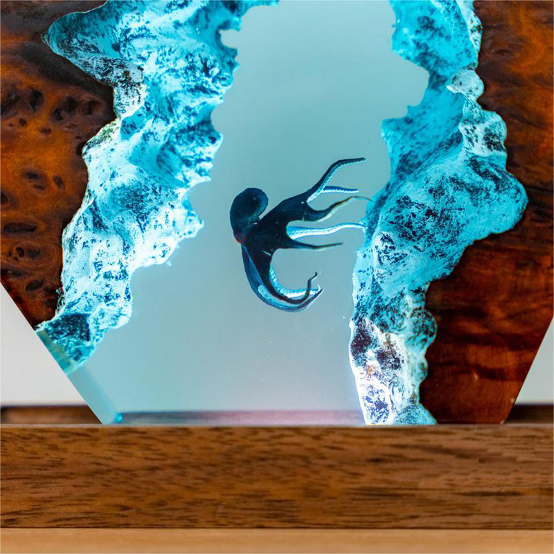 3D octopus night light featuring a dark octopus encased in glowing blue resin between two polished wood edges.