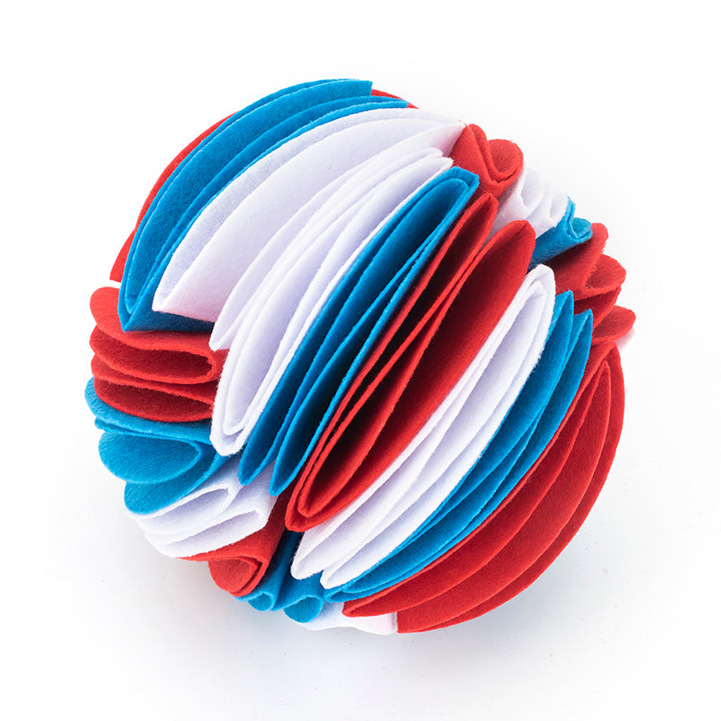 Interactive dog snuffle ball made of layered red, white, and blue felt fabric strips on a white background.
