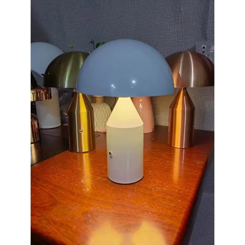 Modern mushroom-shaped desk lamp with a light blue dome shade and white conical base, glowing on a wooden table.