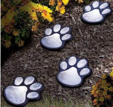 Creative Vault Marketplace solar-powered black plastic bear paw garden lights set in mulch near yellow flowers