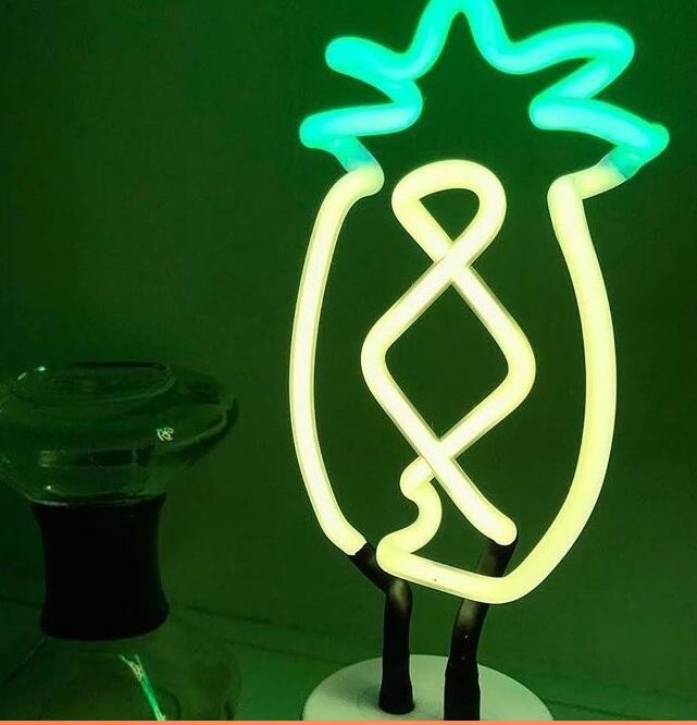 Creative Vault Marketplace pineapple shaped LED neon night light glowing with vibrant green light on a table
