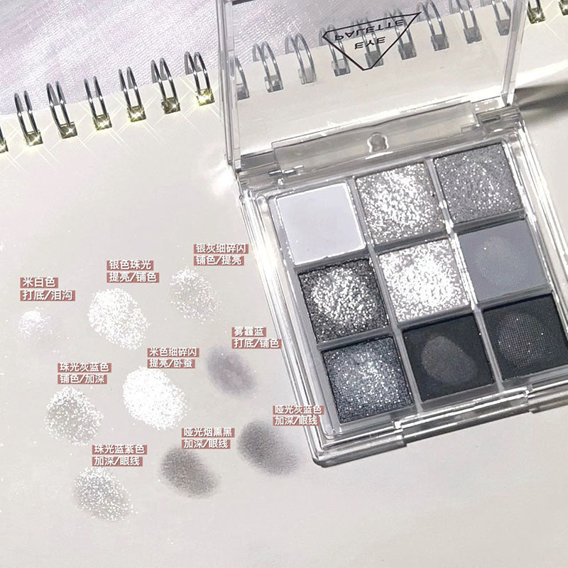 DIKALU 9-color eyeshadow palette in cool grays, silvers, and black with shimmery and matte swatches on paper.