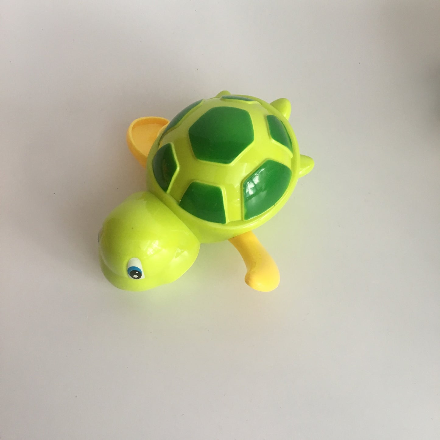 Bright green and yellow plastic wind-up turtle toy with dark green shell patterns, isolated on a white background.