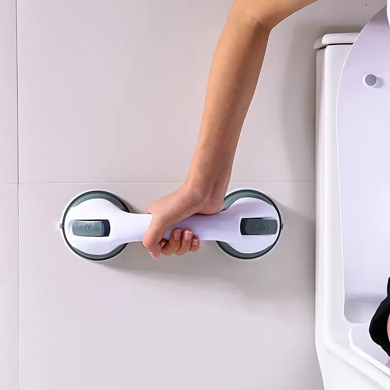 A hand gripping a white and grey suction-cup safety bar attached to a smooth tiled bathroom wall.