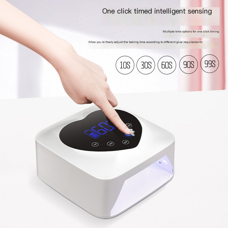 White X20 cordless nail lamp with a heart-shaped top, blue digital display, and finger selecting a 60-second timer.