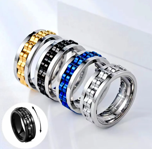 Four titanium steel gear fidget rings in gold, black, blue, and silver, shown aligned with a rotating inset graphic.
