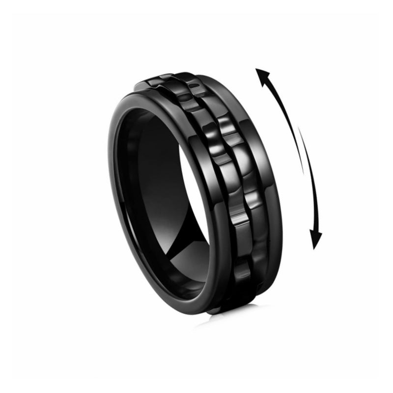 Matte black titanium steel gear fidget ring with a central rotating band, accented by a directional motion arrow.