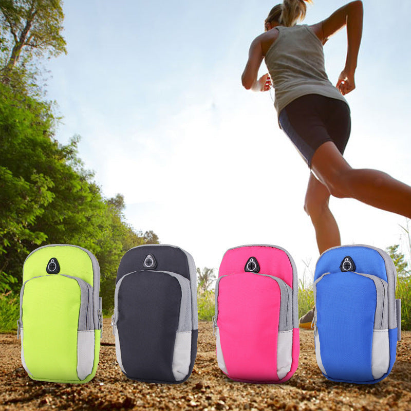 Four colorful sport arm pouches in neon yellow, black, pink, and blue, displayed on a dirt path with a runner.