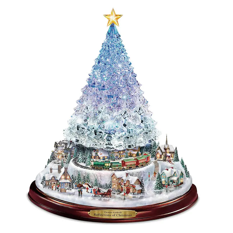 Light-up tabletop Christmas tree with a miniature snowy village, moving train, and gold star topper on a wood base.