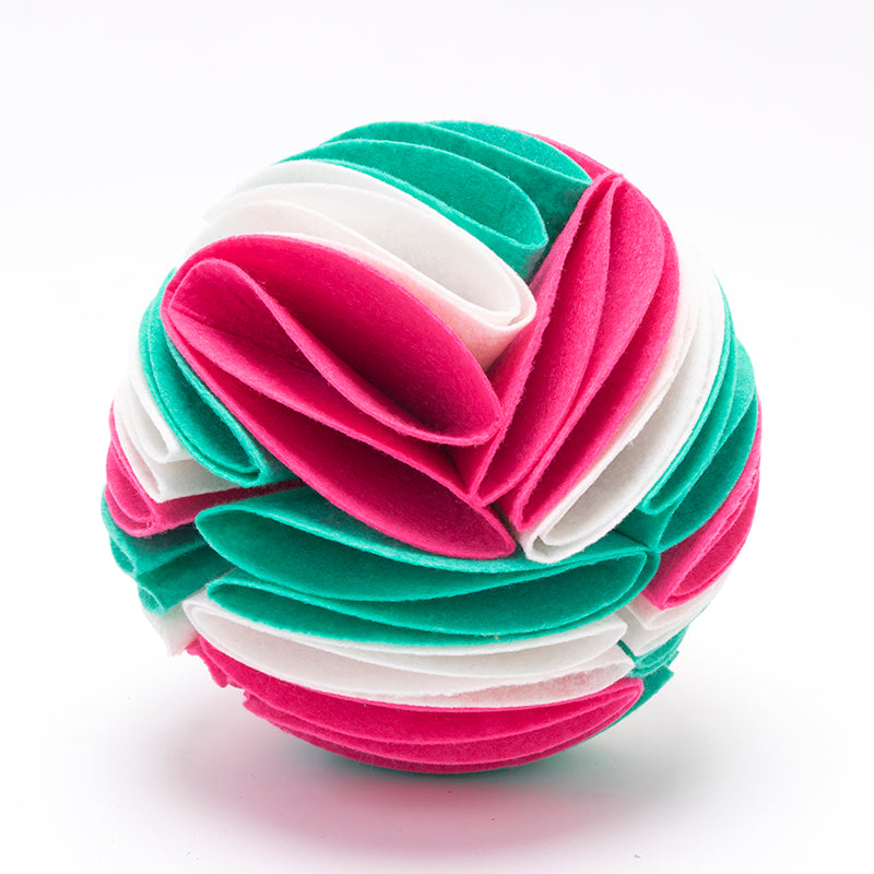 Interactive dog snuffle ball made of layered felt fabric strips in teal, bright pink, and white.
