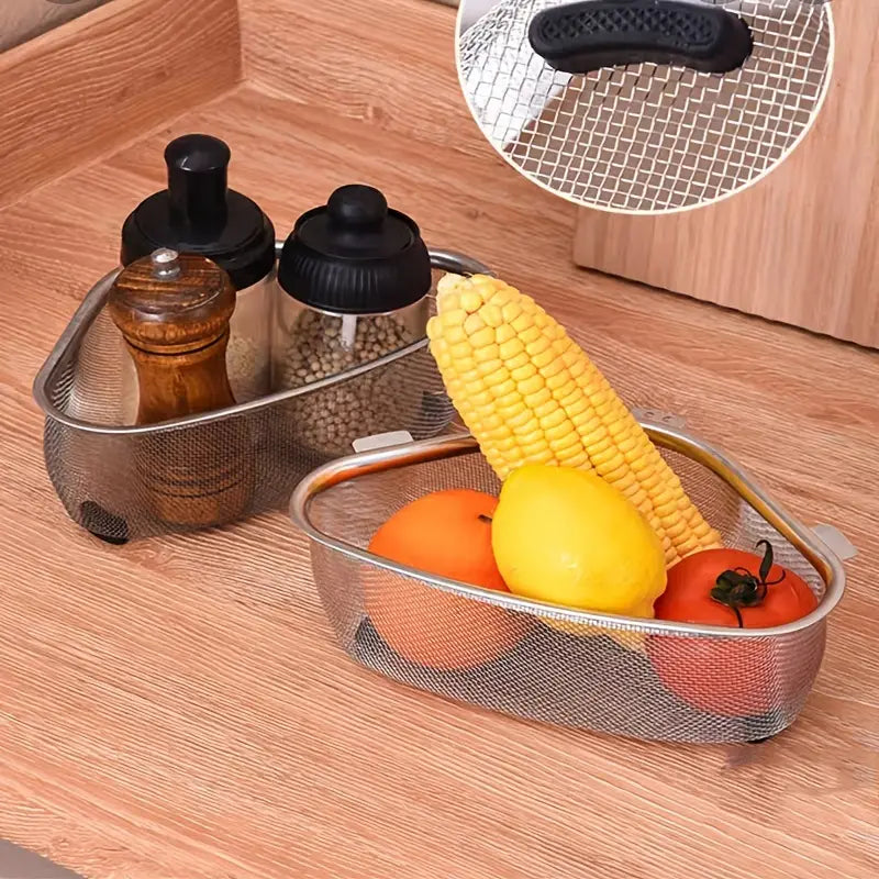 Two triangular stainless steel mesh strainers on a wood surface, holding kitchen spices, corn, lemon, and tomato.