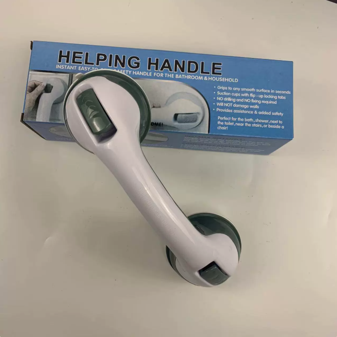 White plastic safety grip bar with green suction cup locking tabs, placed in front of its blue product packaging.
