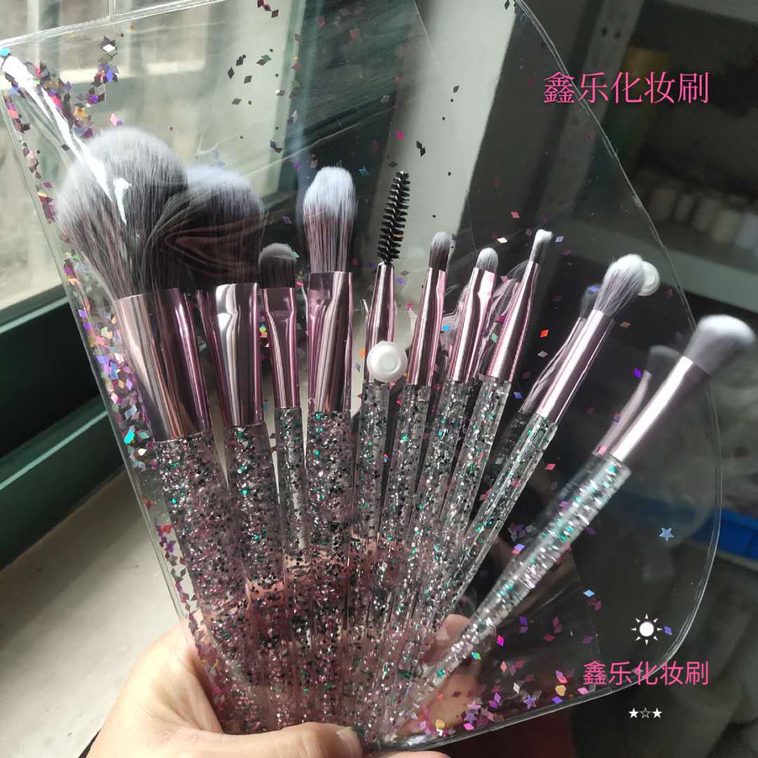 Ten-piece makeup brush set with metallic pink ferrules and clear, glitter-filled handles in a confetti-patterned pouch.